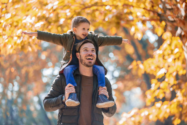 glücklicher vater und sohn spaß im herbst park - jacket child clothing fashion stock-fotos und bilder