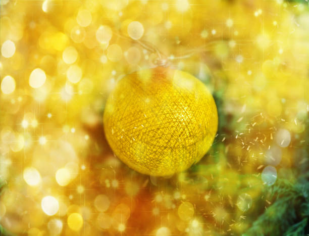 Yellow glowing ball of threads on Christmas tree in bright lights