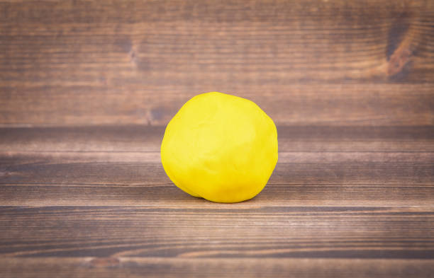 istock Yellow plasticine ball on wood 1064566148
