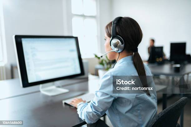Female Customer Service Representative With Headset Working On Computer Rear View Stock Photo - Download Image Now