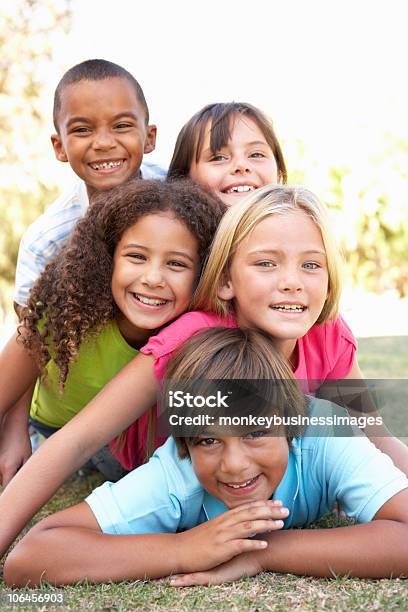 5 Happy Children Of Different Races Piled Up In Park Stock Photo - Download Image Now
