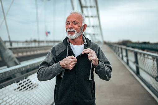 Portrait of a senior runner in a sportswear on the city bridge.