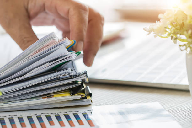 istock Businessman Preparing reports papers with graphs, charts on Stacks of documents files for finance in office. Piles unfinished achieves with paper clip near computer. Concept of Business Annual Report. 1064570866