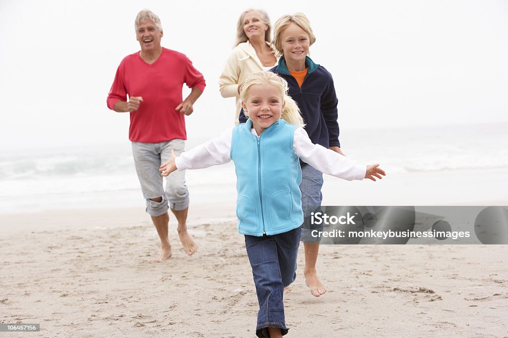 Avós e netos correndo na praia de inverno em - Foto de stock de Família de várias gerações royalty-free