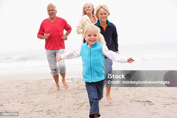 Foto de Avós E Netos Correndo Na Praia De Inverno Em e mais fotos de stock de Família de várias gerações - Família de várias gerações, Avós e Avôs, Exercício físico