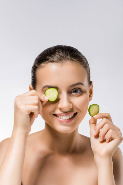 istock young smiling woman with cucumber slice on eye 1064575764