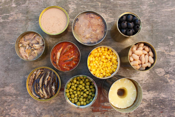 Different open canned food on old wooden background. Top view. Flat lay.