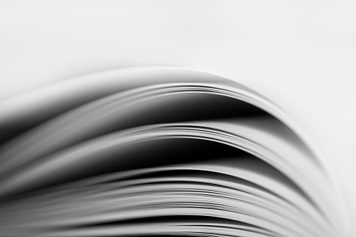 Black and White image of an open book with pages curved.