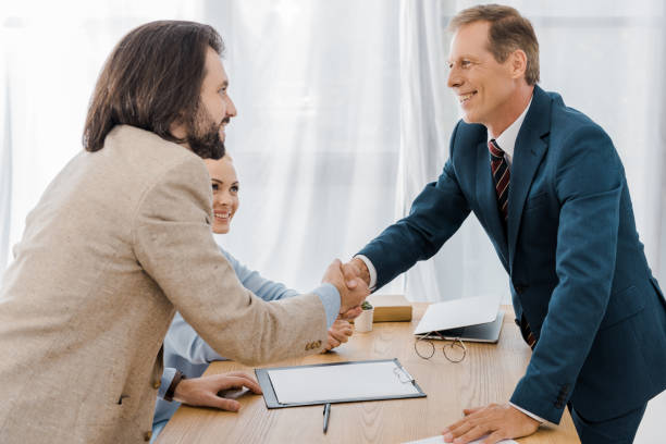 istock happy man and insurance agent shaking hands in office 1064577010