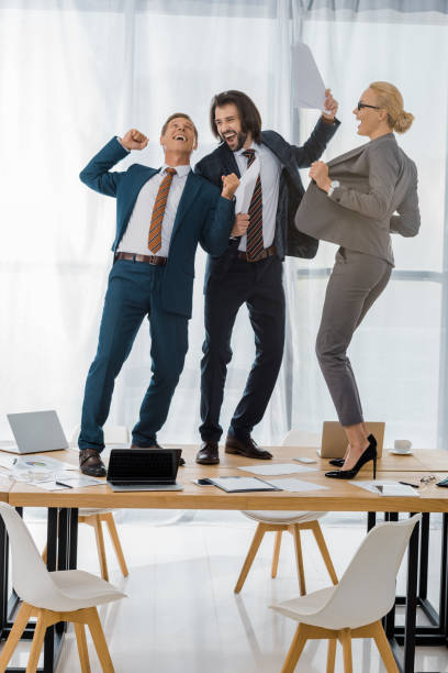 istock joyful insurance workers dancing on table at meeting in office 1064577380