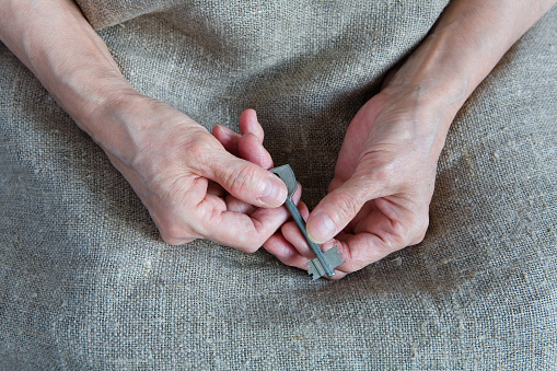 The hands of an old woman hold the key. Close-up.