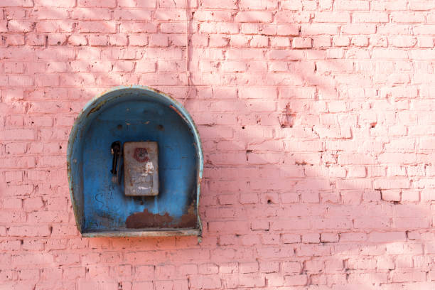 vieux téléphone cassé de la période soviétique sur le mur de briques roses - pay phone brick wall telephone old photos et images de collection
