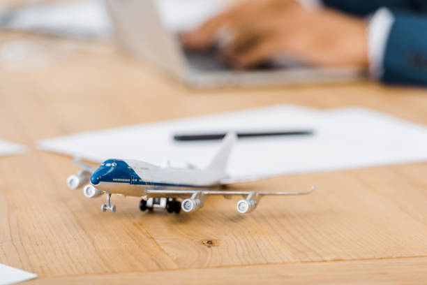 istock toy airplane at wooden table with office worker using laptop on blurred background 1064582840
