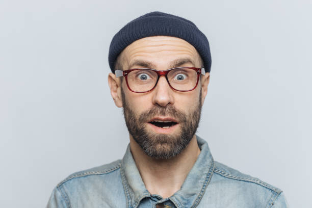 istock Horizontal shot of amazed excited shocked man stares at camera with unexpected expression, keeps mouth opened, hears awful news, isolated over grey background. Omg and great surprisment concept 1064585786