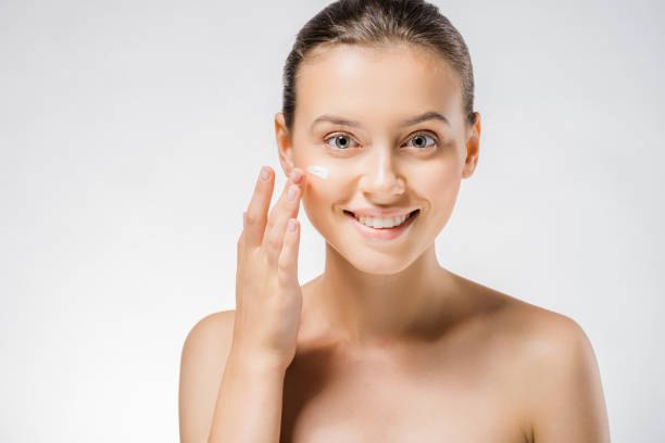 istock young beautiful woman applying white cream on face 1064586478