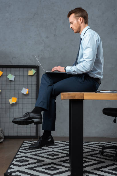 istock confident businessman sitting on table and working on laptop in modern office 1064592196