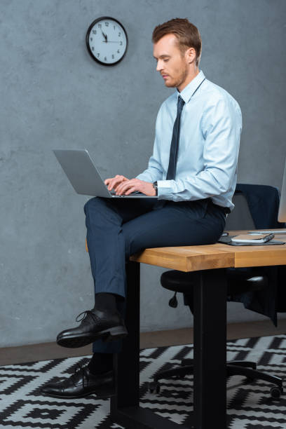 istock serious businessman sitting on table and working on laptop in modern office 1064592212