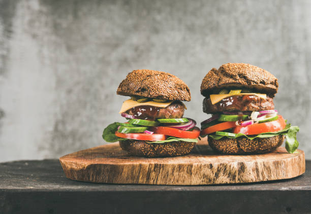 istock Beef meat cheeseburgers with barbeque sauce on board, copy space 1064593582