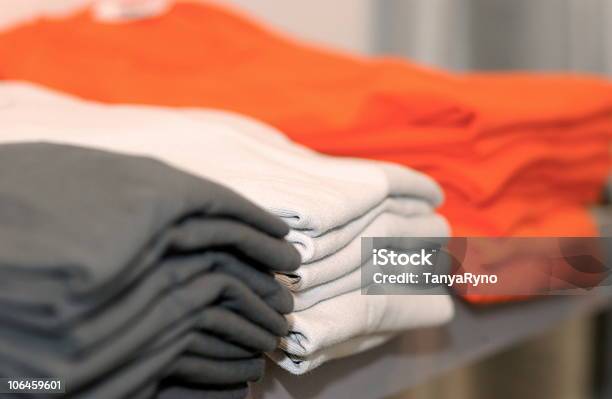 Three Piles Of Shirts In Dark Gray White And Bright Orange Stock Photo - Download Image Now