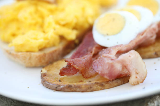fried egg with crispy bacon stripes on plate, on wood table