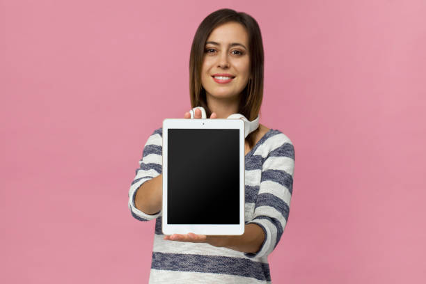 istock Young woman showing note on tablet against pink background 1064603764