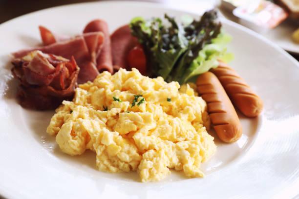 istock Breakfast scrambled egg with bacon sausage and salad on wood background 1064608166