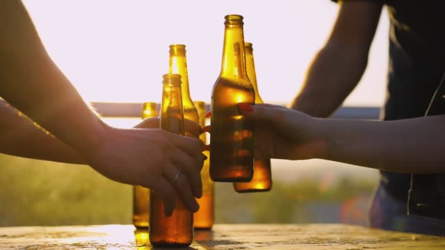Friends Drinking Beer Outdoors. Bottles In Hands Closeup