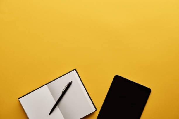 istock top view of opened notebook and tablet on yellow surface 1064613712