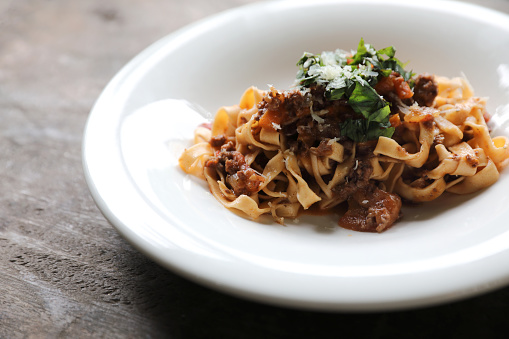 Pasta Fettuccine Bolognese with beef and tomato sauce on wood background in dark tone mystic light style