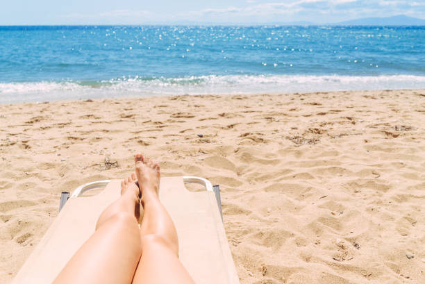 istock Female legs sunbathing on the beach 1064618088