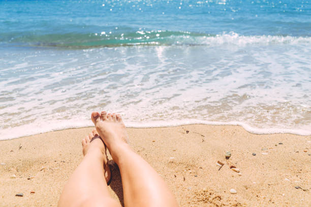istock Female legs sunbathing on the beach 1064618432