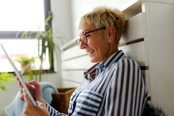 istock Smiling beautiful senior woman using digital tablet at home 1064632196