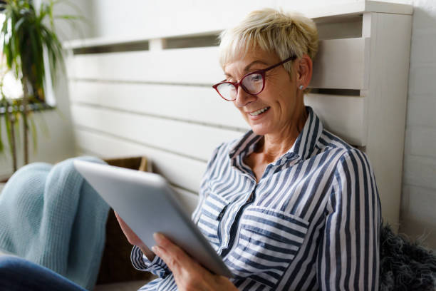 istock Smiling beautiful senior woman using digital tablet at home 1064632470