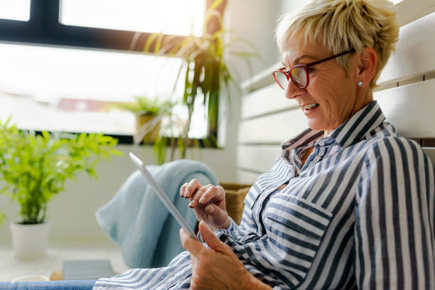 istock Smiling beautiful senior woman using digital tablet at home 1064632556