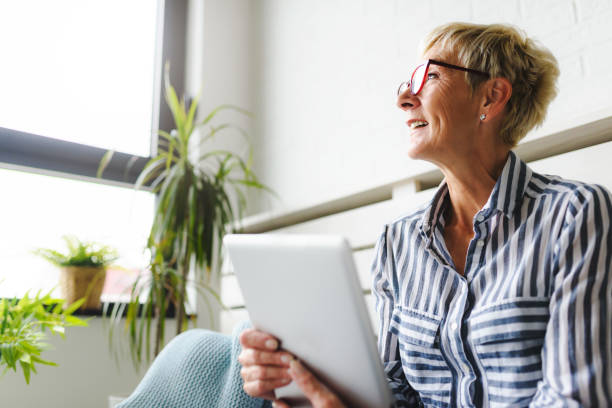 istock Smiling beautiful senior woman using digital tablet at home 1064632694