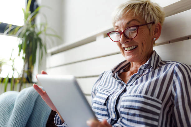 istock Smiling beautiful senior woman using digital tablet at home 1064632712