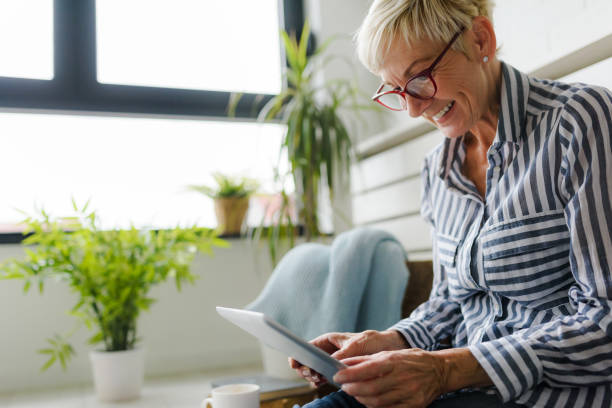 istock Smiling beautiful senior woman using digital tablet at home 1064632916
