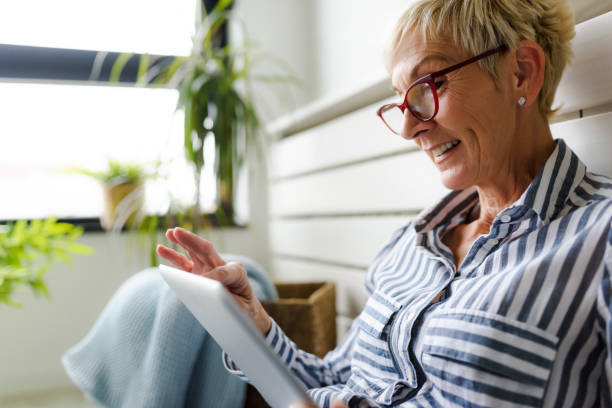istock Smiling beautiful senior woman using digital tablet at home 1064634000