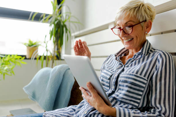 istock Smiling beautiful senior woman using digital tablet at home 1064634010