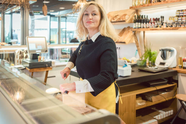istock Shop clerk in deli cutting cheese 1064642124