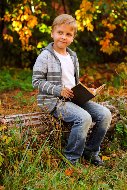 istock boy sitting in the woods on a log 1064642212