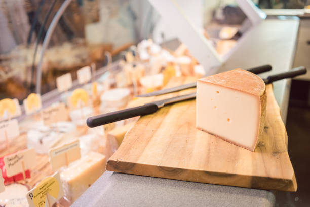Cheese on a board at counter in delicatessen shop or deli
