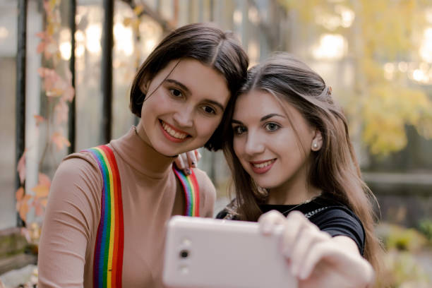 istock Two beautiful students taking selfie on the phone in the autumn park 1064646526