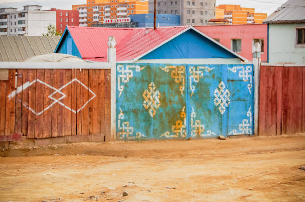 Ulaanbaatar, Mongolia - July 9, 2010: Typical dirt side street with fences protecting property with houses & apartment blocks behind in the capital city of Mongolia.