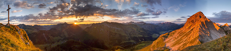 Mountain panorama at dawn with orange color and clouds in the sky