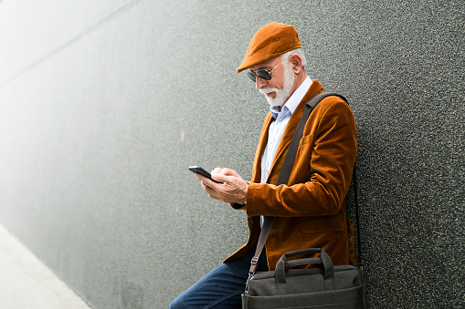 Fashionable Senior Man Outdoors using smart phone