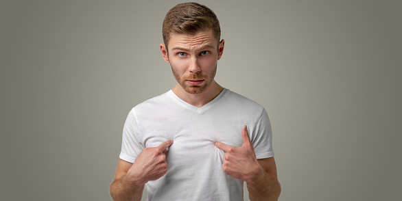 Surprised puzzled the man wrinkles his brow in disbelief and pointing fingers at his chest. Studio portrait on isolated background.