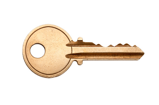 A blank brass key against a white background