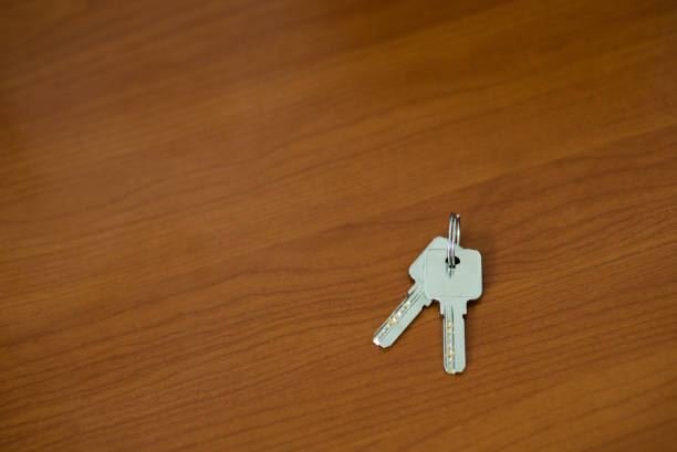 house key in the front door. Close up the key in the lock. There is a hallway in the  background. The key ring has a house icon on it.