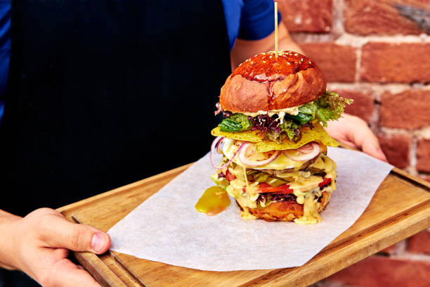 istock tall, big burger on a tray in hands 1064669898